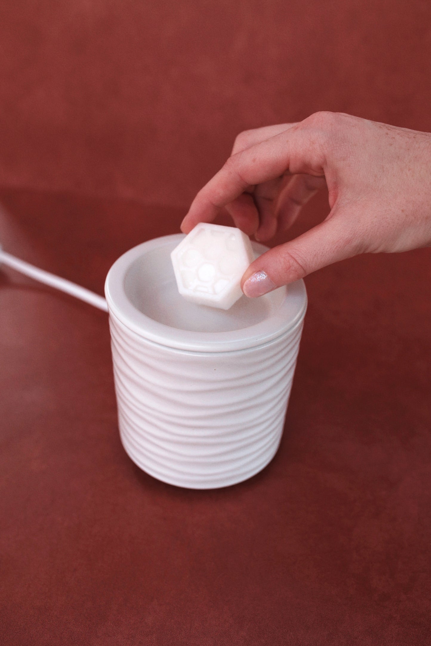 hand placing wax melt into white wavy wax warmer