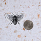 save the bees sticker next to a quarter for size comparison