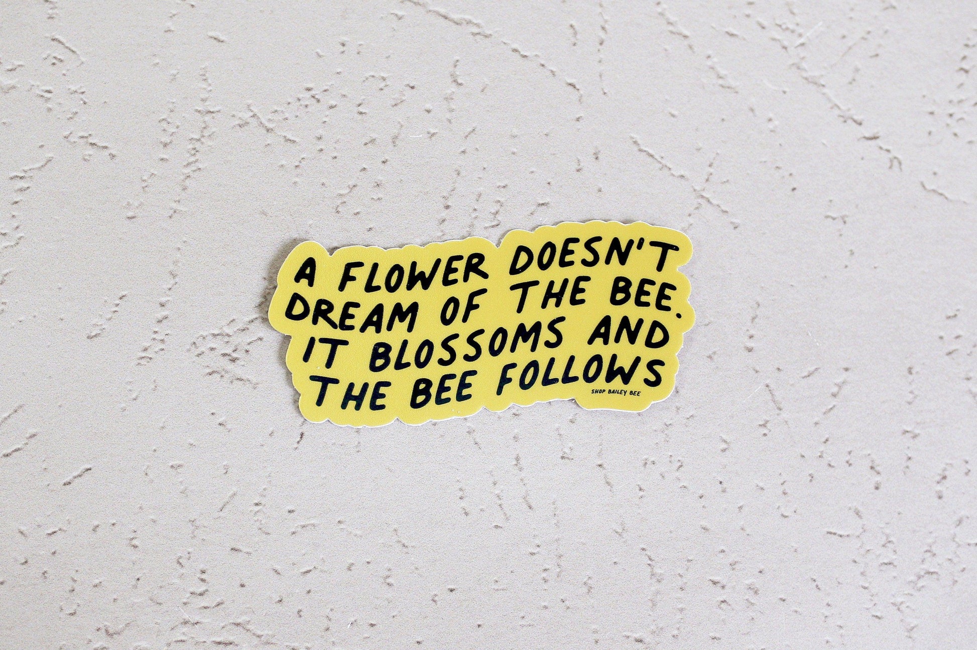 a flower doesn't dream of the bee it blossoms and the bee follows against pale pink backdrop